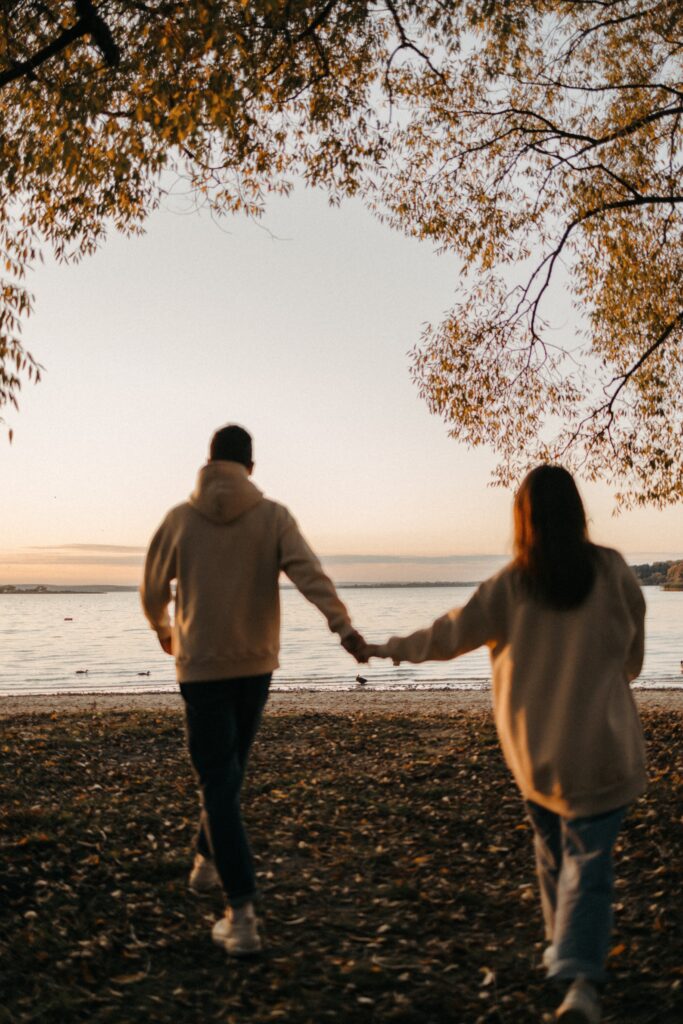 Image of two people holding hands near a lake - Rendé - conversation starters and date ideas