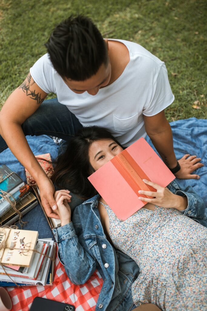 Image of two people reading on a picnic blanket - Rendé - conversation starters and date ideas