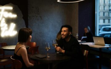 Man and woman at dimly lit restaurant. The man is holding a wine glass.